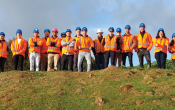 Group of works in hi vis on top of a hill smiling